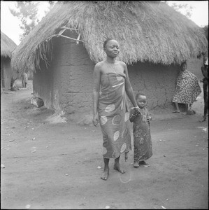 Young African woman with her baby in front of a hut