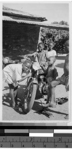 Five boys around a motorcycle, Africa, October 1949