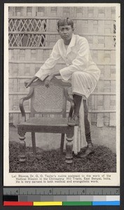 Man standing outdoors by a wooden chair, India, ca.1920-1940