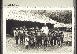 A village schoolteacher in front of the school with his pupils