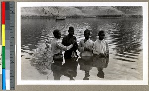 Indigenous pastor baptizing three men in a river, Vārānasi , India, ca. 1920