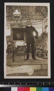 Missionary standing at front of village church, Guyana, ca.1910/1920