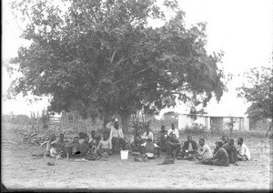 Men drinking an alcoholic beverage under a tree, Ricatla, Mozambique, ca. 1896-1911
