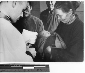 Rev. Comber baptizing a baby in Fushun, Manchuria, China, 1938