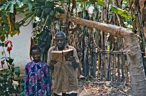 ELCT, Nordveststiftet, Tanzania, 1984. Evangelist Simon Kibarabara med Bibelen. Da billedet blev taget, var han 84 år og enkemand. Da han blev pensioneret i 60-års alderen, fik han en Bibel i pension. Ellers fik han ingen pension, det fik kun præsterne. Missionær Gudrun Larsen spurgte, om han ikke var ked af, at han fik Bibelen og ikke en pension, som han kunne leve af? Han svarede: 'Nej, hvis jeg havde fået en håndfuld penge, så havde jeg bare brugt dem, men nu har jeg fået Guds levende ord'. Simon Kibarabara og hans kone var til stor støtte for Gudrun Larsen - opmuntrede hende, når hun havde brug for det, og satte hende i rette, når det var det, hun havde brug for