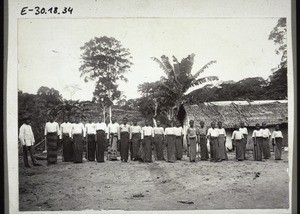 Pupils of the Boys' Boarding School in Bombe, Cameroon. With Rev. Greule. Doing Gymnastics with wooden staves