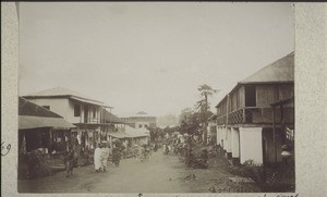 Another street in Kumase with numerous shops. The tree on the right stands by the entrance of what used to be the kings palace. The high house is a trading store standing at a place which used to be called 'mogyawoe' meaning 'never dry of blood', one of the main execution places