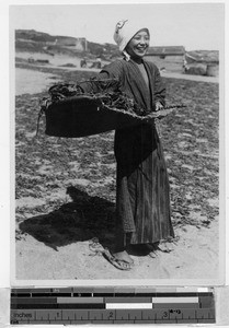 Girl carrying mat full of dried indigo leaves, Japan, August 1932