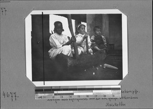 African girl and the two Bachmann children pounding wheat, Mbozi, Tanzania, ca. 1908-1916