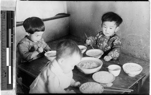 Three young orphans eating a meal, Fushun, China, 1936