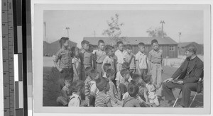 Fr. Leo Stenbach talks to children at Japanese Relocation Camp, Manzanar, California, October 29, 1944