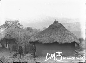 Swiss missionaries standing in front of huts, South Africa, ca. 1896-1911