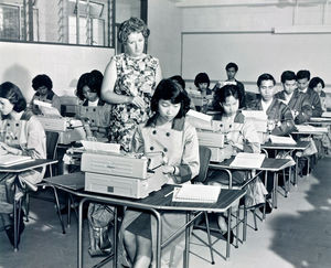 Kwun Tong Vocational Training Centre i Hongkong blev grundlagt i 1965 af LWF/LWS’s regionale afdeling – på et tidspunkt hvor "byen var så fattig, at det var almindeligt for velgørende organisationer at uddele gratis mælkepulver". Centret blev gennem mange år pioner for en række erhvervsfaglige kurser, med henblik på at sikre studerende fra lavtlønnede familier et levebrød. De forskellige fag blev løbende tilpasset den aktuelle udvikling i samfundet. Et af de første kurser var et diplom-program i fotografering, som blev meget efterspurgt. Dette foto - der viser studerende på Kwun Tong Erhvervsfaglige Center - er taget, fremstillet og printet af studerende på centret