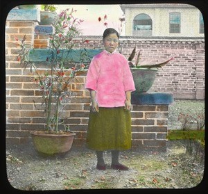 Female student standing by brick wall, China, ca.1917-1923