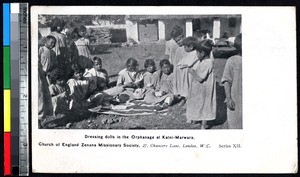 Orphaned girls dressing dolls and other children watching, Katni, India, ca.1900-1920