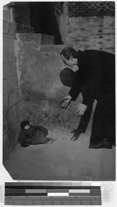 Missionary reaching for a baby, China, ca. 1910-1930