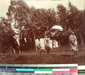 Ole Jensenius on horseback and two children on a carrying chair, Madagascar