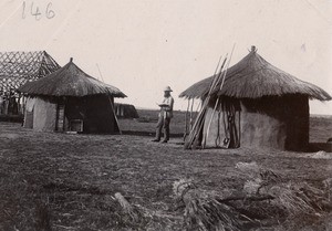 Missionary Georges Volla in front of traditional huts