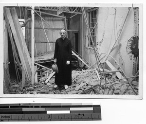 Fr. Downs stands amidst wreckage at Shantou, China, 1938