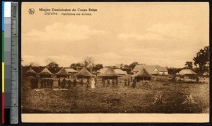 School children stand in line near a row of huts, Doruma, Congo, ca.1900-1930