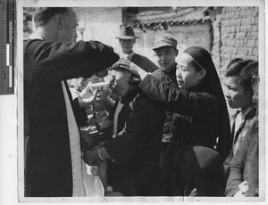 Maryknoll priest baptizing a woman at Wuzhou, China