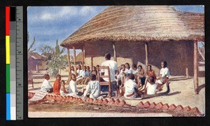 Teacher sitting with schoolboys outside a thatched building, Malawi, ca.1920-1940