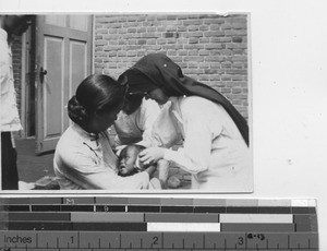 Sister Paula Sullivan helps a sick child at Fushun, China, 1934