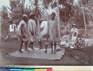 Four men dancing on a mat in the garden while missionary children are watching, Soatanana, Madagascar, 1906-1909