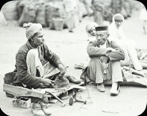 Boot mender, India, ca. 1930