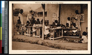 Children working at desks on the porch of the school, Niangara, Congo, ca.1900-1930