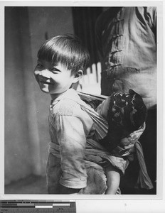 A child carrying a baby at Wuzhou, China, 1949