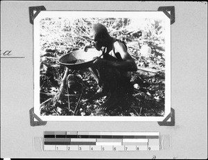 A man blowing dust out of a bowl, Nyasa, Tanzania, 1937