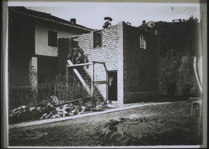 Chinese masons building a house. Concrete wall 1 metre high. Above this they have built with stones made from earth - like the bricks of the old Israelites in Egypt. Brick pillars at the corners