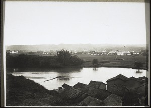 Limtshai (Aussenstation v. Fophin). Im Vordergrund ein Teil des Marktes, dann der Fophin-Fluss, dann Reisfelder bis zum Dorf, das aber keine geschlossene Bauweise hat, es sind Felder zwischen den Häusergruppen