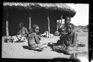 African people sitting in front of a hut, Mozambique, ca. 1940-1950