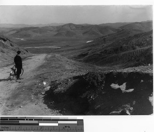 Fr. Geselbracht bikes through the hills at Fushun, China, 1940