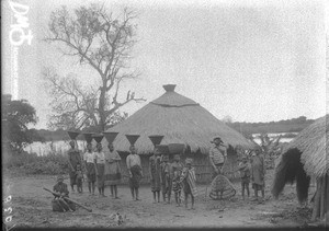 Group of African people in front of a hut, Makulane, Mozambique, ca. 1896-1911