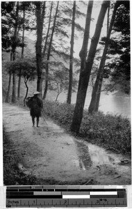 Man walking on a dirt road next to a river, Japan, ca. 1920-1940