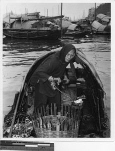 Old woman guiding boat in Hong Kong harbor, China