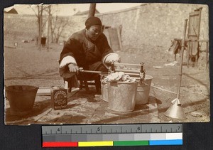 Woman operating a hand-cranked washer outdoors, China, ca.1905-1910