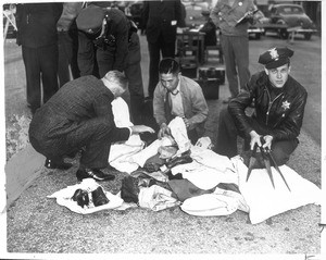 "Alarm spread yesterday when officers examining evacuees' baggage discovered knives wrapped in belongings of Kisuki Okasaki"--caption on photograph