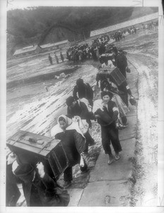 "Carrying luggage and babies, long line of repatriates wends way over catwalk, last stage of trip from China where some have been in exile. Others had never seen homeland."--caption on photograph