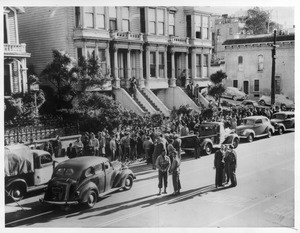 "A number of SF Japs crowd Bush St. sidewalk in preparation for their transfer to evacuation center for them at Tanforan--Soldier escorts shown forground."--caption on photograph