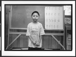 Young boy of Filipino origin, in classroom, standing in front of blackboard, SOMA, San Francisco, California, 2002