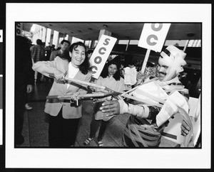 Woman cutting tape off of man with gardening shears at demonstration, Industrial Areas Foundation, Los Angeles, 1996