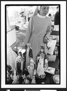 Statues of Jesus and Mary on a table top, with nun of Vietnamese origin standing behind at Our Lady of Peace, San Jose, California,2002