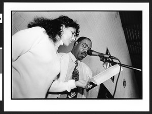 A young woman and man singing during Mass, Langley Park-McCormick Elementary School, Hyattsville, Maryland, 2002