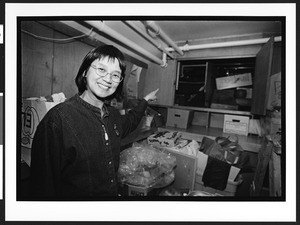 A woman of Chinese origin points to a cupboard leading to a tunnel, used as a hiding place for runaway Chinese immigrants in the 1800's in the basement of Cameron House, Chinatown, San Francisco, California,2002