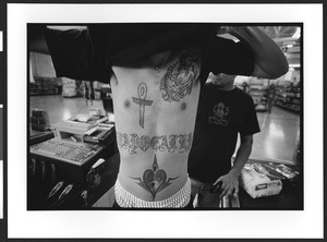 Young man of Hispanic origin showing off his tattoo on his stomach and chest, San Salvador