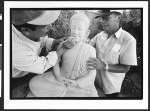 Two men of Vietnamese origin cleaning statue of Buddah, Chua Duc Vien Pagoda, or Perfect Harmony Temple, San Jose, California, 2002